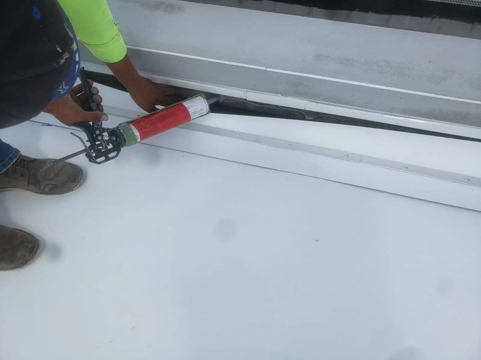 Authentic client technician applying commercial polyurethane sealant to expansion joint
